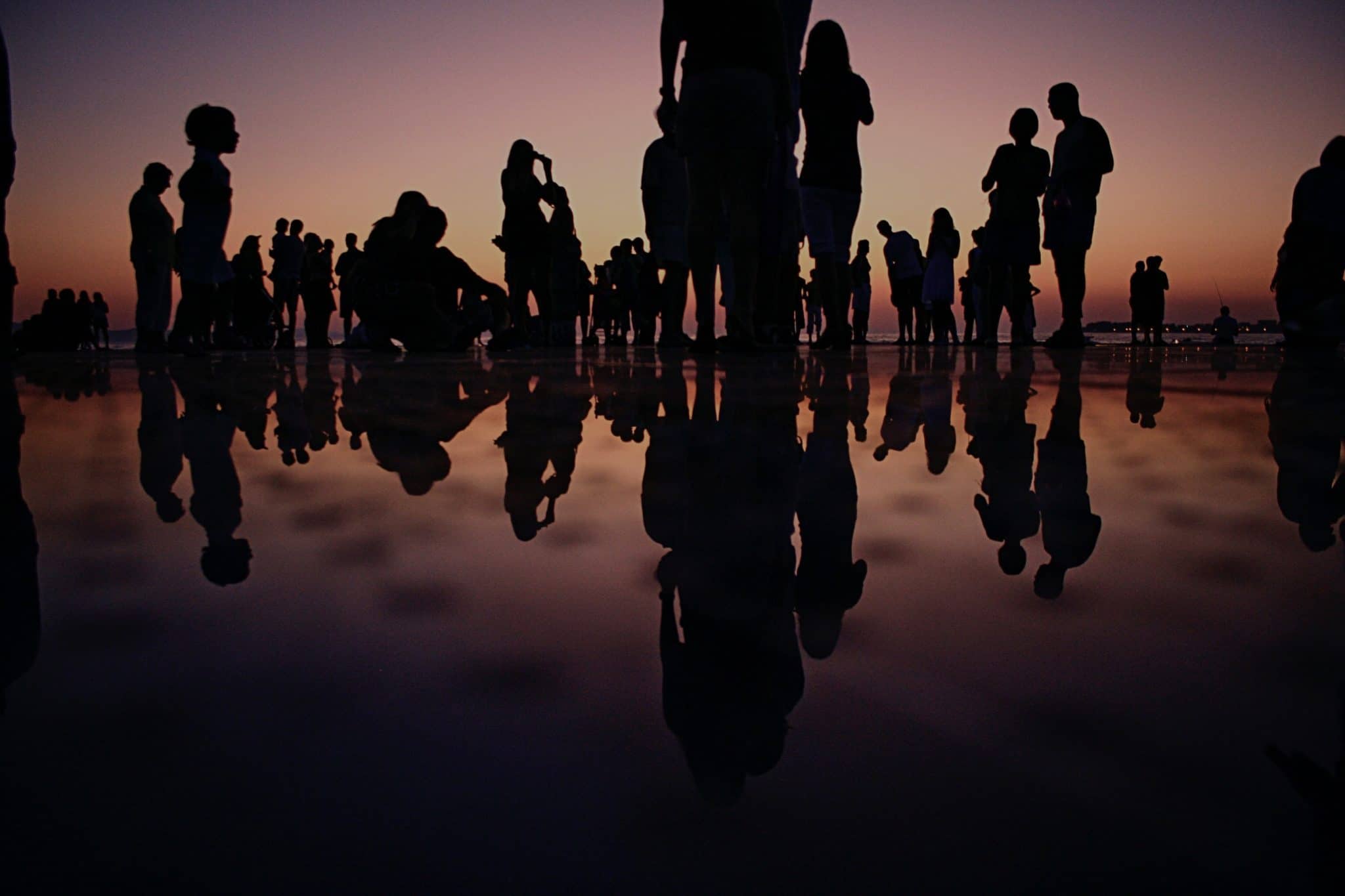 People standing on a shoreline in dark silhouette