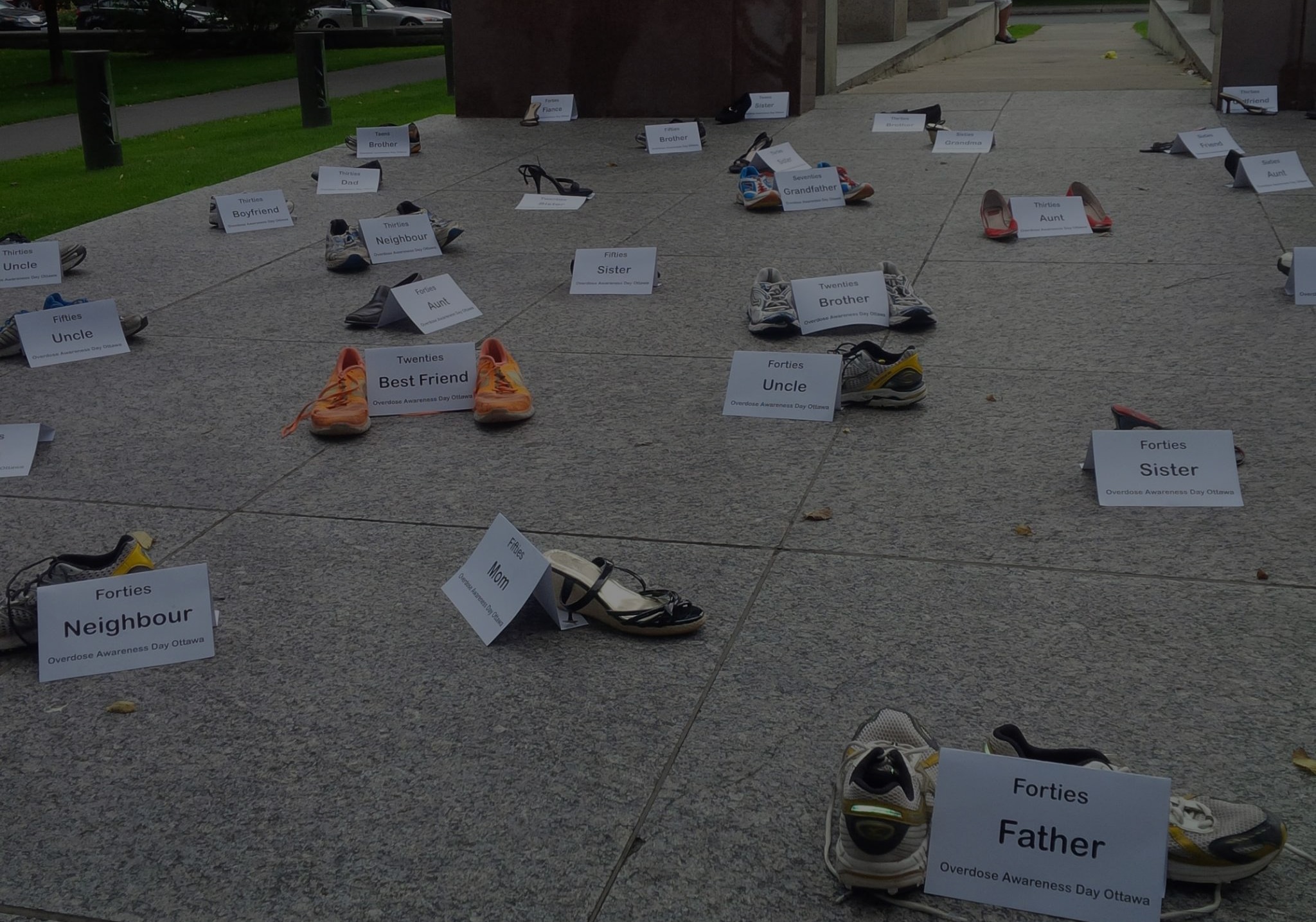 Shoes on the pavement with signs representing people who have died from overdose