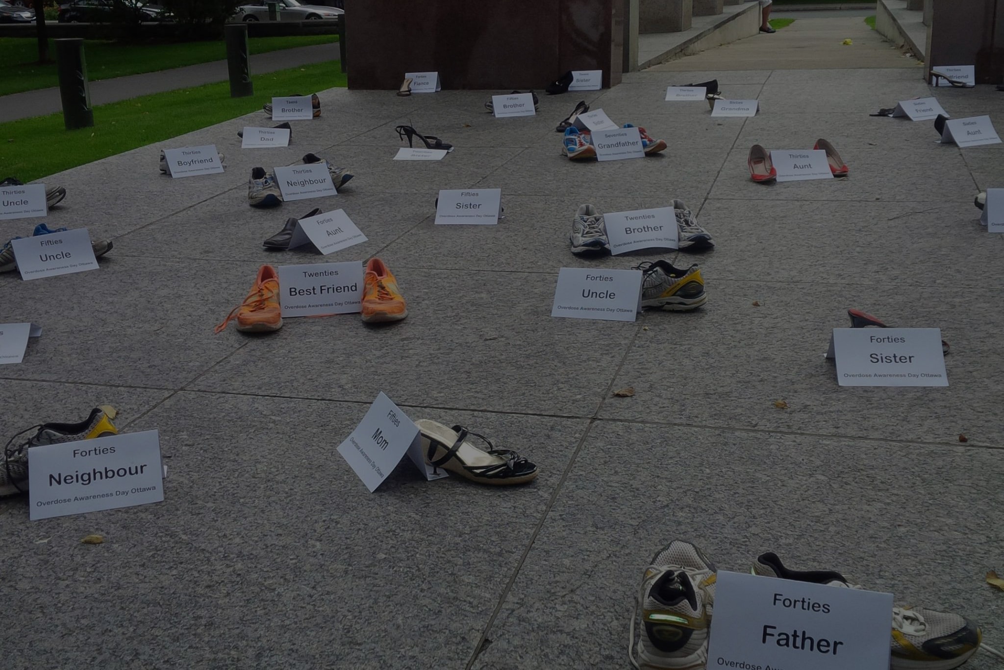 Shoes with white cards written with names of the deceased arranged along the pavement