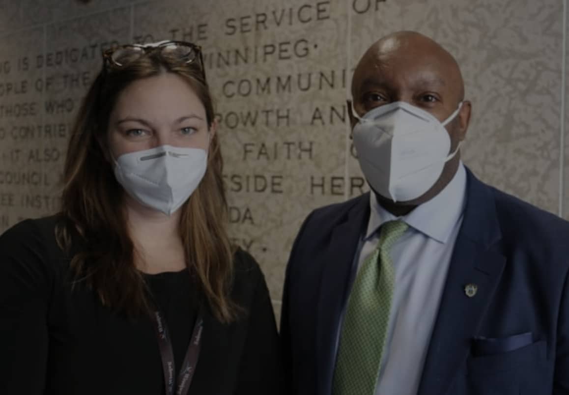 Two Winnipeg city councillors, a young woman and man, standing wearing medical face masks